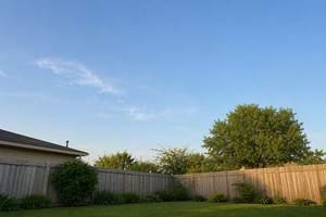 An empty backyard sky above a fence
